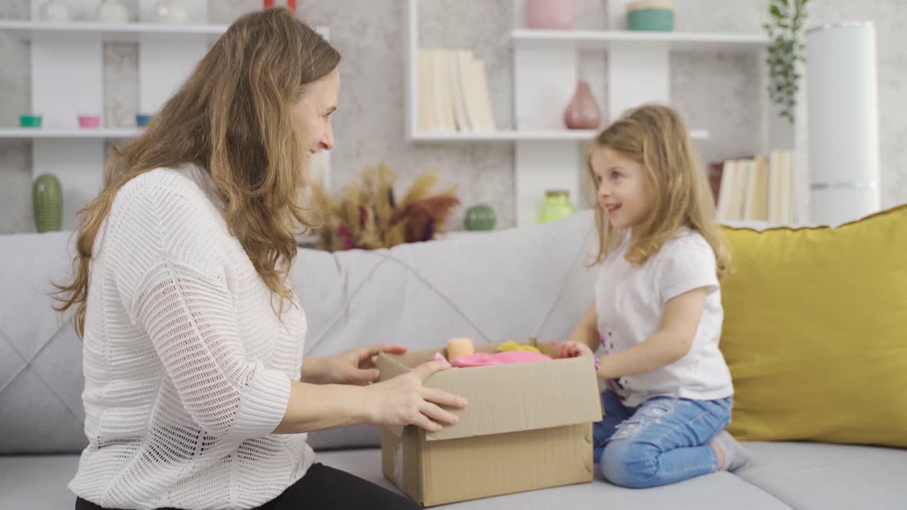 madre le da muñecas a su hija pequeña.