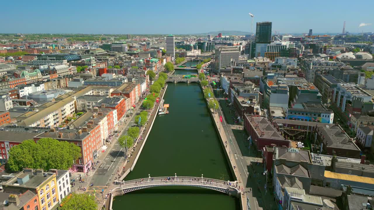 Wide overhead aerial video of the River Liffey, the Ha'penny Bridge and Dublin City Centre in Dublin, Ireland on a bright and sunny day. Filmed in 4K, 60FPS and with Rec709 color.