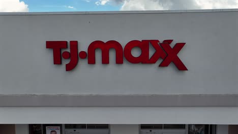 tj maxx storefront building in american shopping center. clothing, handbag, home decor. aerial backwards shot. man with kid leaving shop.