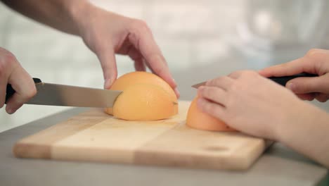 mother hand cutting grapefruit slice. woman and kid hands cutting citrus fruit