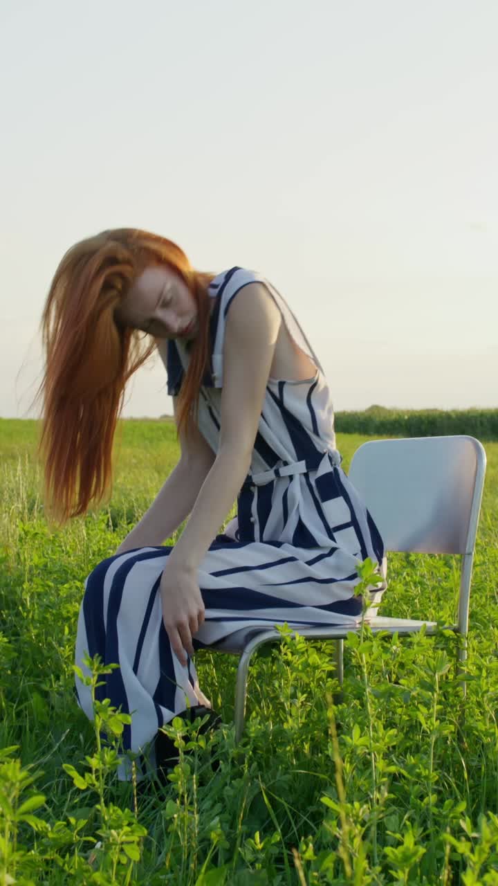 들판 에 앉아 있는 줄무 의 드레스 를 입은 여자