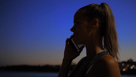 Una-Mujer-Hermosa-Que-Detiene-Su-Trote-Nocturno-En-La-Playa-De-Bondi,-Australia,-Para-Responder-Una-Llamada-Telefónica---Lento