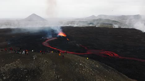 vista aérea de personas mirando la erupción volcánica en litli-hrutur, islandia, con lava fresca y humo saliendo