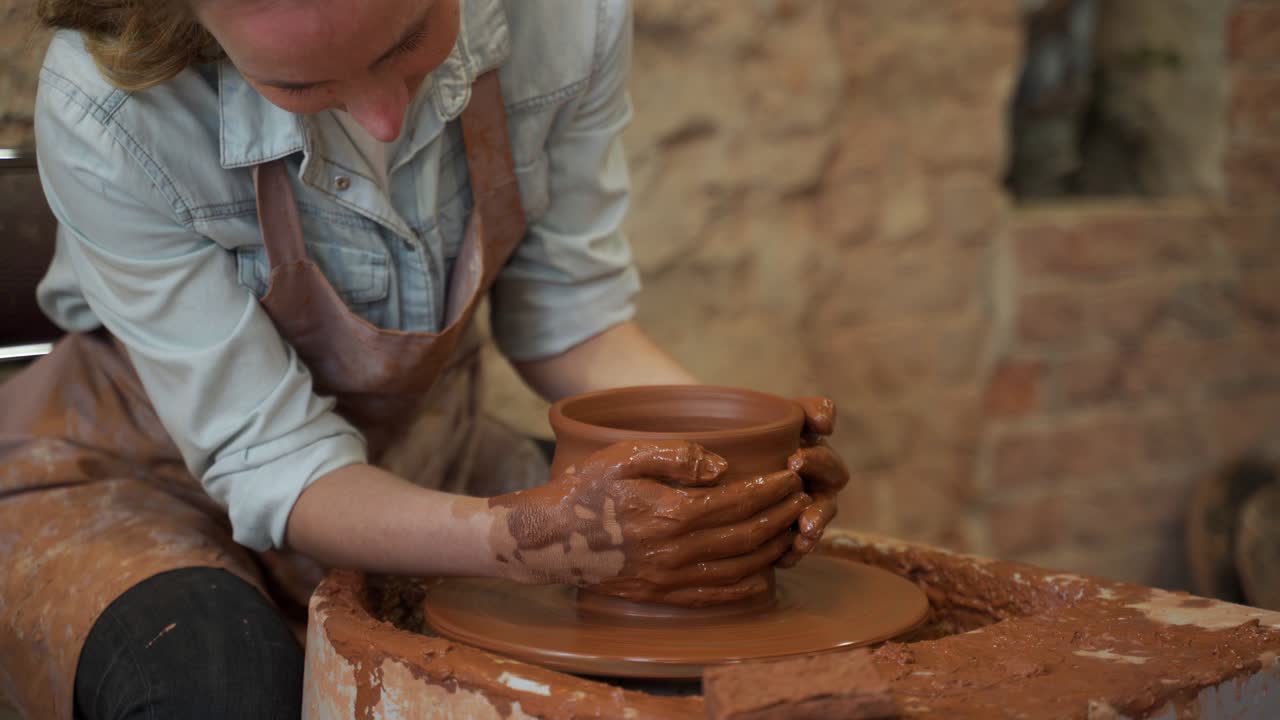 Donna ceramista che lavora al tornio creando un vaso di argilla. Maestra che modella l'argilla con le mani creando un vaso in un laboratorio