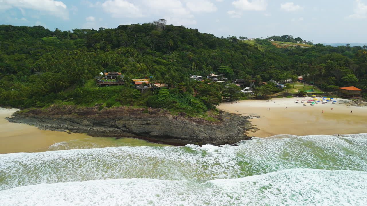 Aerial view rising away from tropical bungalows on the coastline of Itacare, Brazil