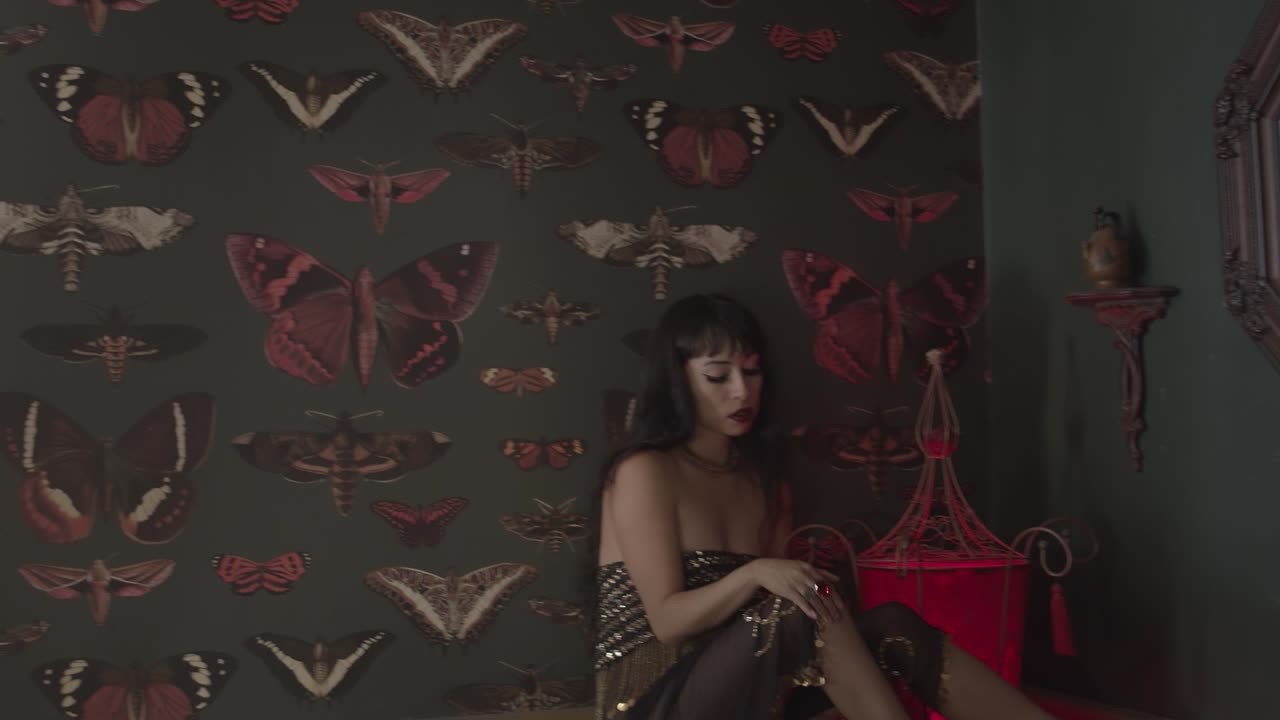 어두운 빈티지 방에 앉아 반짝이는 드레스, 표현력 있는 화장, 매혹적인 표정을 지닌 고딕 소녀