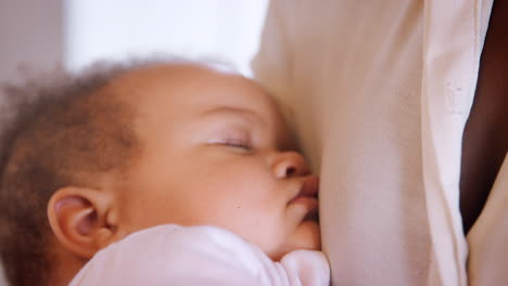 Close-Up-Of-New-Mother-Cuddling-Sleeping-Baby-Girl-In-Nursery-At-Home