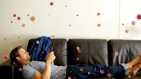animación de iconos de frutas sobre un hombre caucásico usando un teléfono inteligente