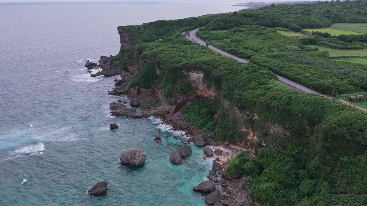 Cảnh quay trên không ngang di chuyển chậm dọc theo bờ biển gồ ghề của Vách đá Muiga và Cối xay gió năng lượng gió, Miyakojima, Okinawa, Nhật Bản