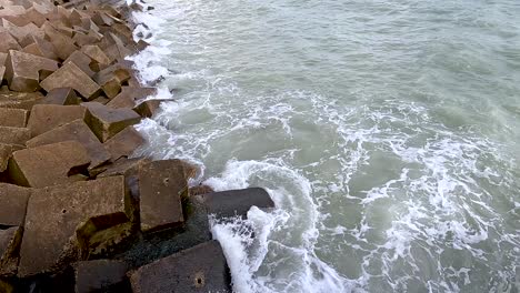 waves hitting concrete blocks on the shore