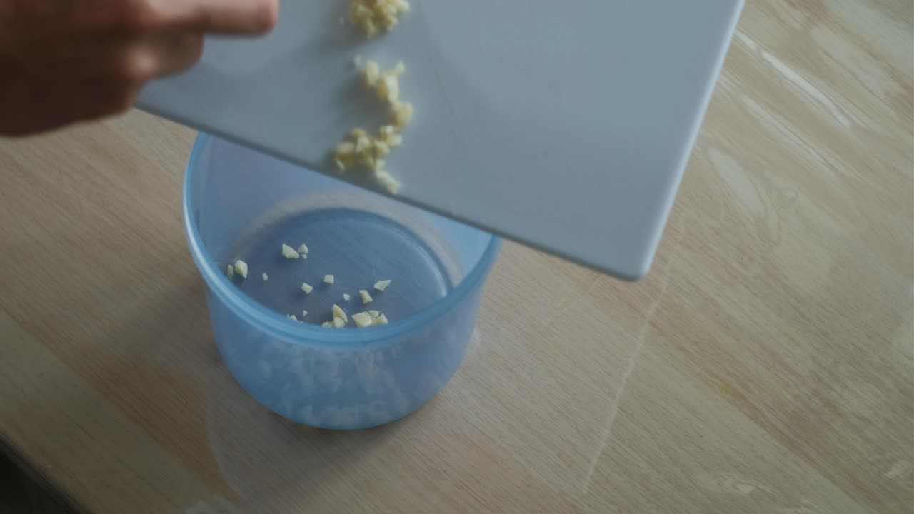 Pouring Minced Garlic into Storage Container – Close-Up Shot