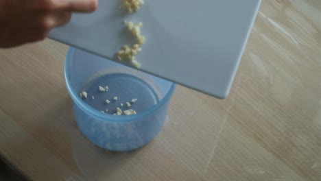 pouring minced garlic into storage container – close-up shot