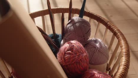 looking down on knitting equipment in a basket wool and needles sunlit living room