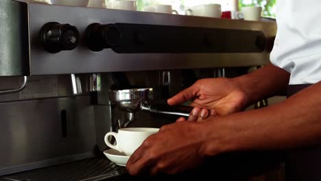 Mid-section-of-waiter-making-cup-of-coffee-at-counter-in-cafe