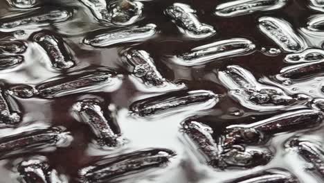 close-up view of a wet metal plate with a diamond pattern