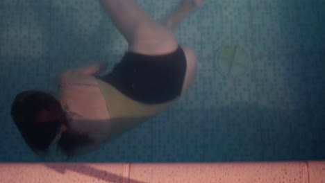 una mujer joven gira y nada bajo el agua lejos de la cámara