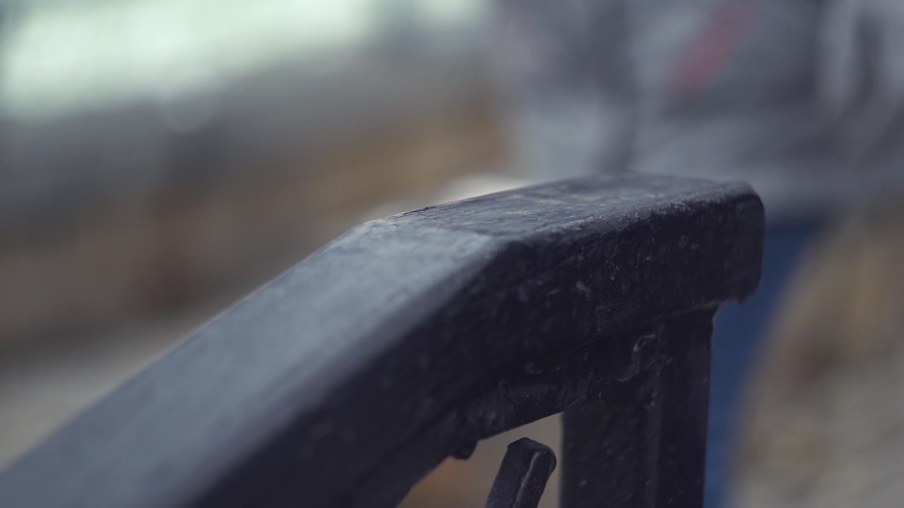 회색 장갑을 입은 사람이 검은 나무 드레일을 만지고 있습니다.