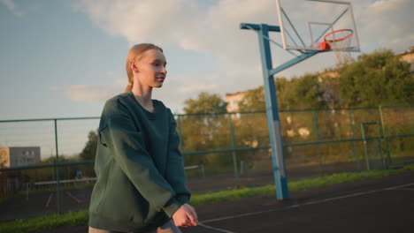 un jugador de voleibol participa en una sesión de entrenamiento con un aro de baloncesto, un edificio y árboles en el fondo durante el anochecer, mostrando enfoque, energía y atletismo en un entorno dinámico al aire libre