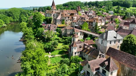 Small,-medieval-village-situated-next-to-a-river,-flowing-through-a-rich-forest-in-the-heart-of-France