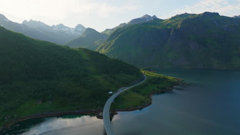 cinematic aerial footage of the austertraumen bridge on the lofoten islands in sunset time with wild and unique mountains in the background, norway, europe