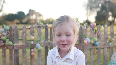 un niño vestido con un atuendo temático de pascua sonríe y abraza a su conejito de peluche