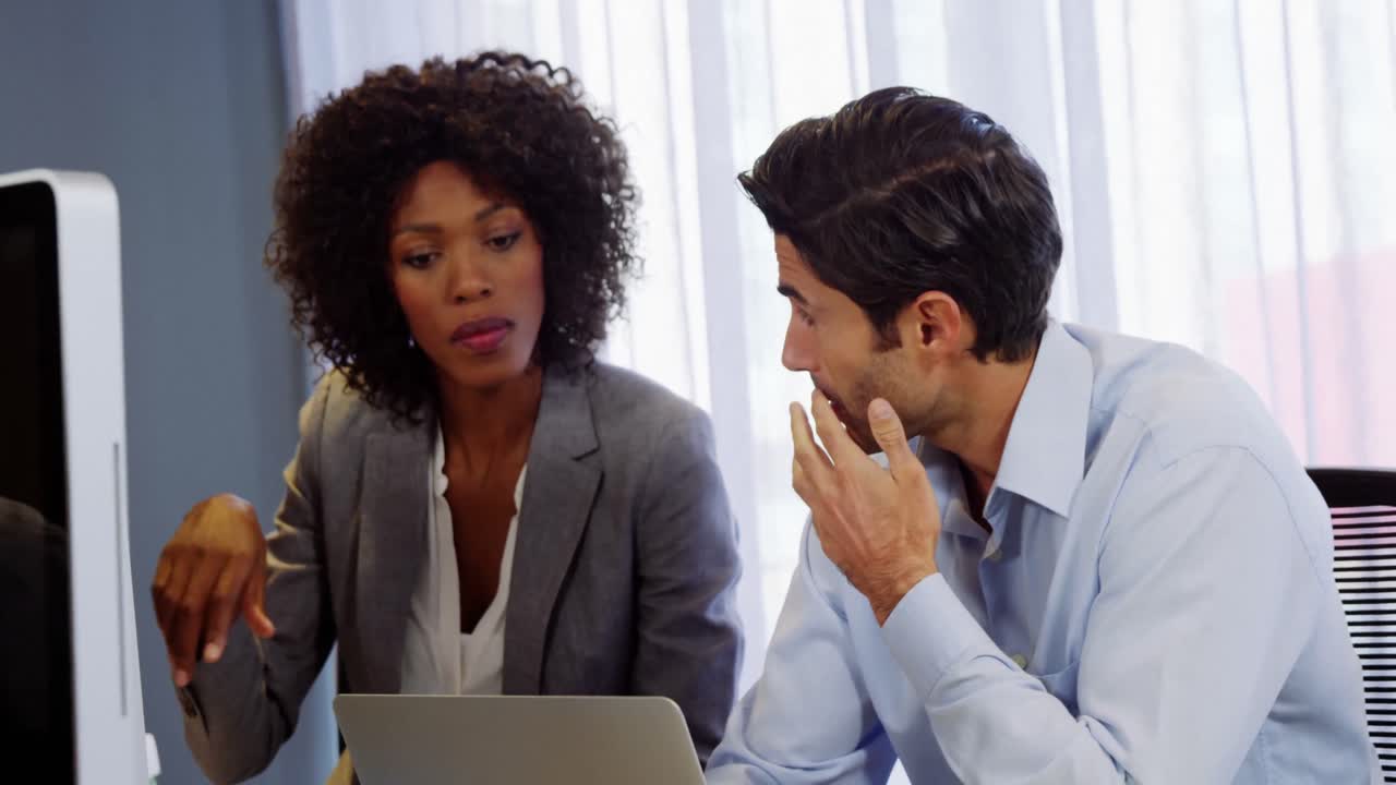 un hombre de negocios y una mujer de negocios discutiendo en una computadora portátil.