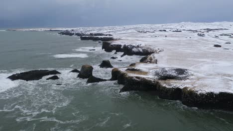 aerial drone shot showing beautiful coastline with ocean and snowy landscape in snæfellsnes,iceland