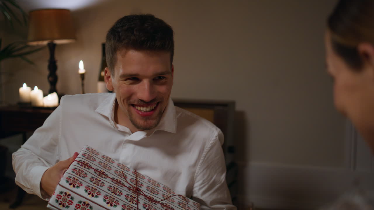 긍정적 인 남자가 불 내부에서 선물을 주고, 여성이 선물을 흔들고