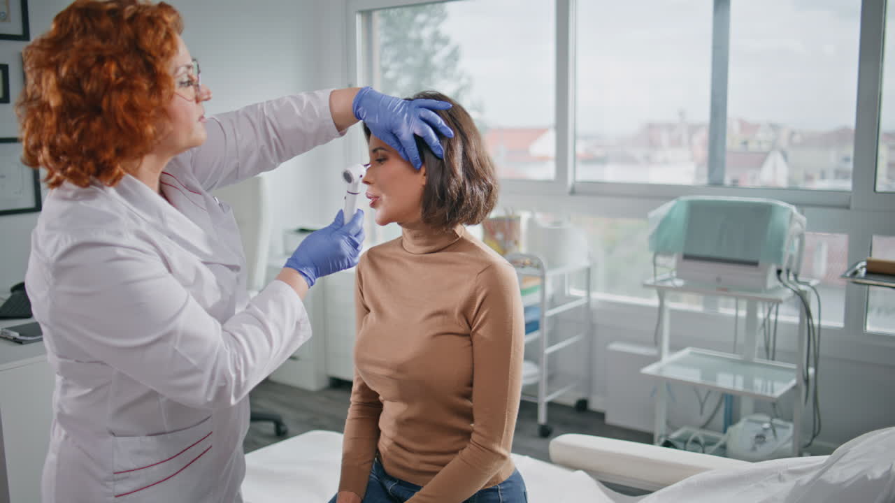 Clinic practitioner looking ears woman patient with equipment. Health checkup