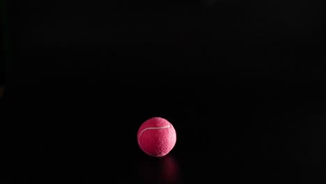 a tennis ball bounces on a dark surface