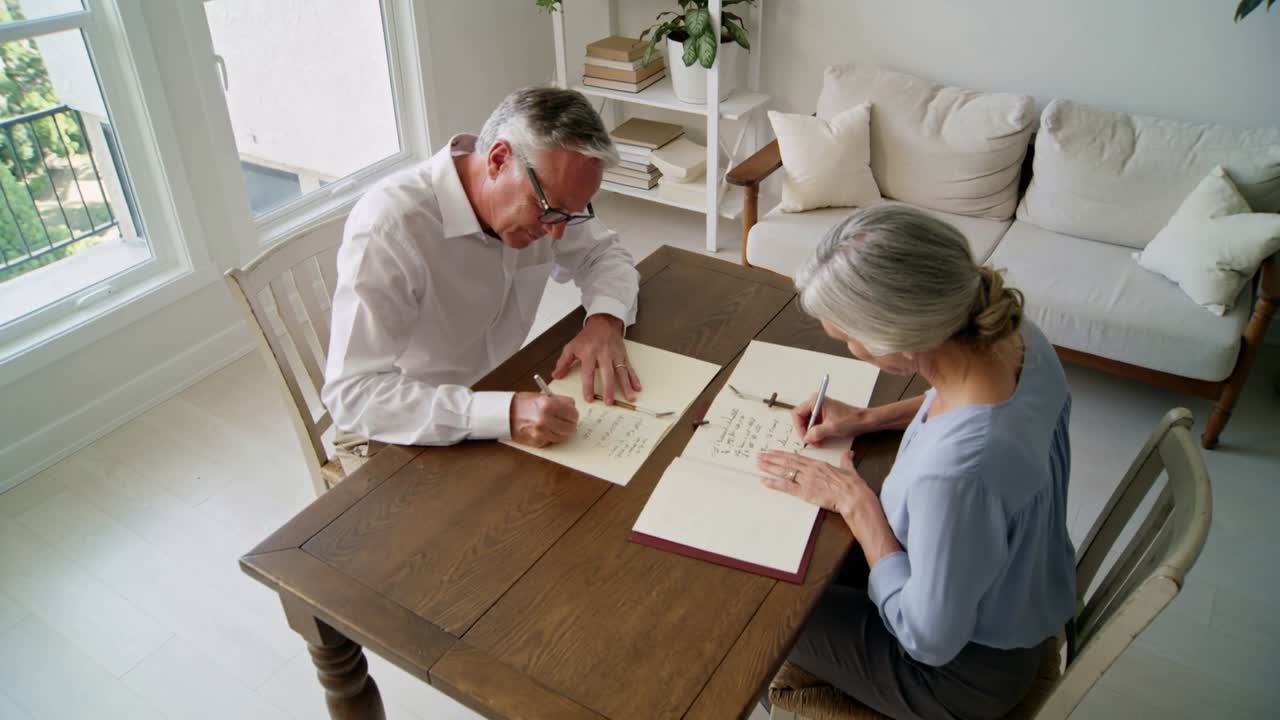 Abriendo una carpeta roja, pareja escribiendo y firmando formularios en la mesa del comedor de casa, hombre con camisa blanca
