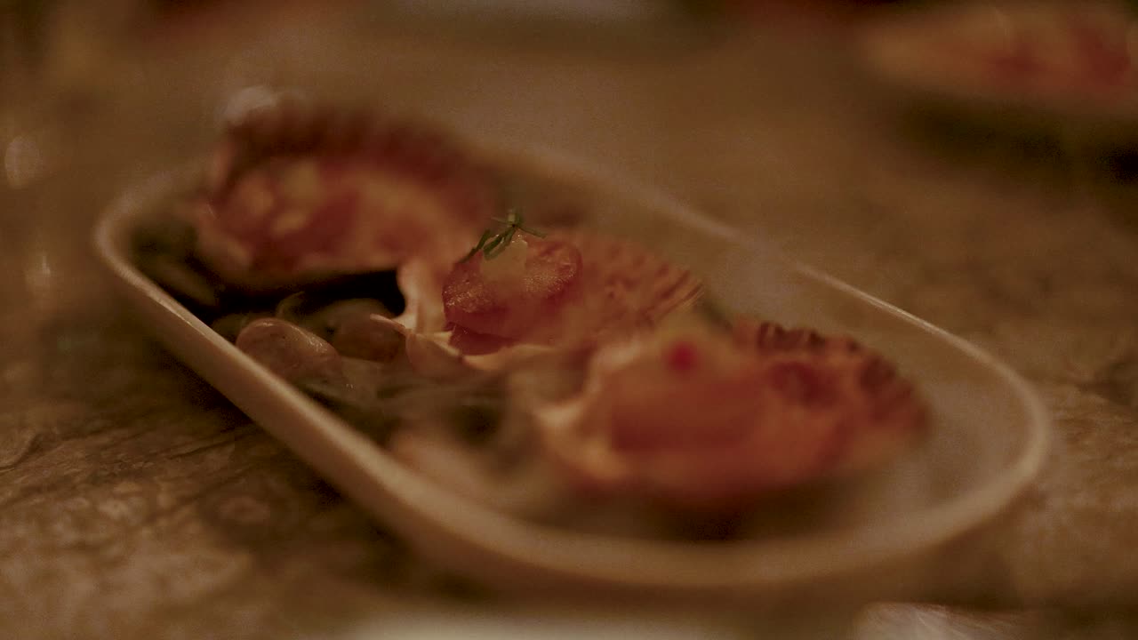 Close-up of grilled scallops on a plate, captured in warm, ambient lighting with a shallow depth of field