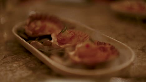 close-up of grilled scallops on a plate, captured in warm, ambient lighting with a shallow depth of field