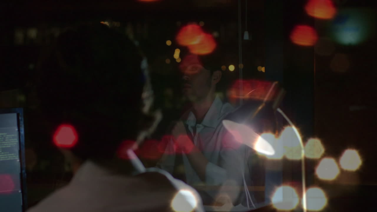 Man coding at night in technology office, with glowing desk lamp and floating code lines