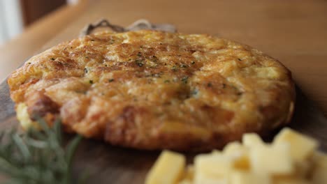 potato and cheese omlete, wide pan, decorated rustic wooden plate with rosemary