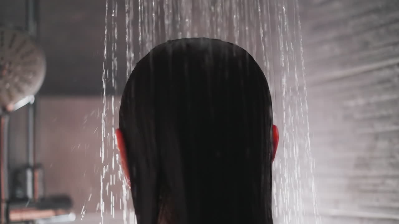 dama se encuentra bajo el flujo de agua en la ducha. mujer con cabello moreno se encuentra en la ducha comenzando a lavar el cabello. rutina matutina para la mujer ama la ducha