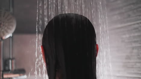 dama se encuentra bajo el flujo de agua en la ducha. mujer con cabello moreno se encuentra en la ducha comenzando a lavar el cabello. rutina matutina para la mujer ama la ducha