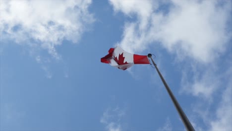 Bandera-Canadiense-Ondeando---Ondeando-En-Un-Cielo-Azul-Nublado,-En-Cámara-Lenta