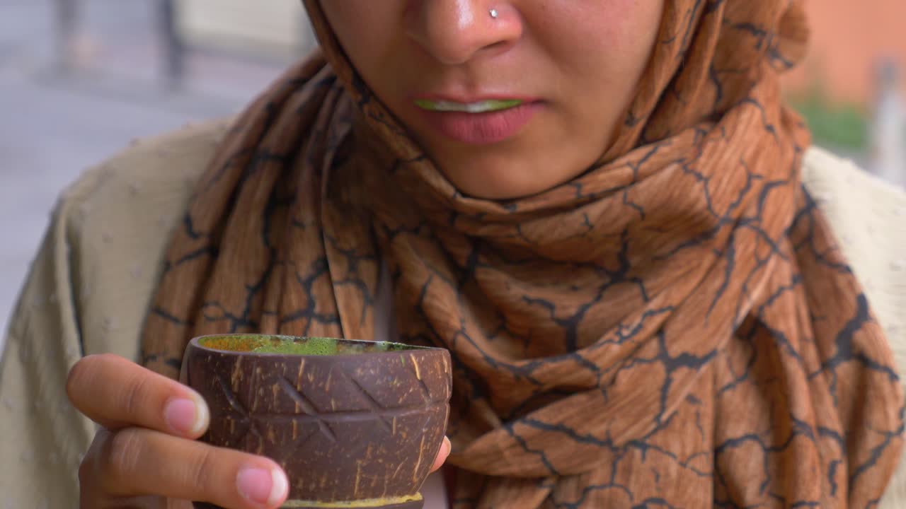 mujer bebiendo de una taza de cáscara de coco