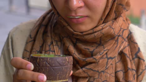 woman drinking from a coconut shell cup