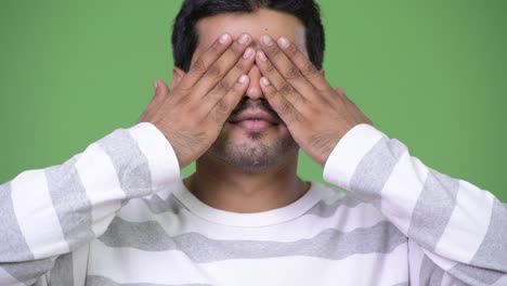 young handsome persian man covering eyes as three wise monkeys concept