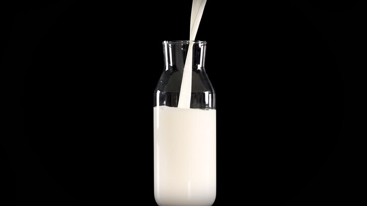 Milk being poured into a glass bottle