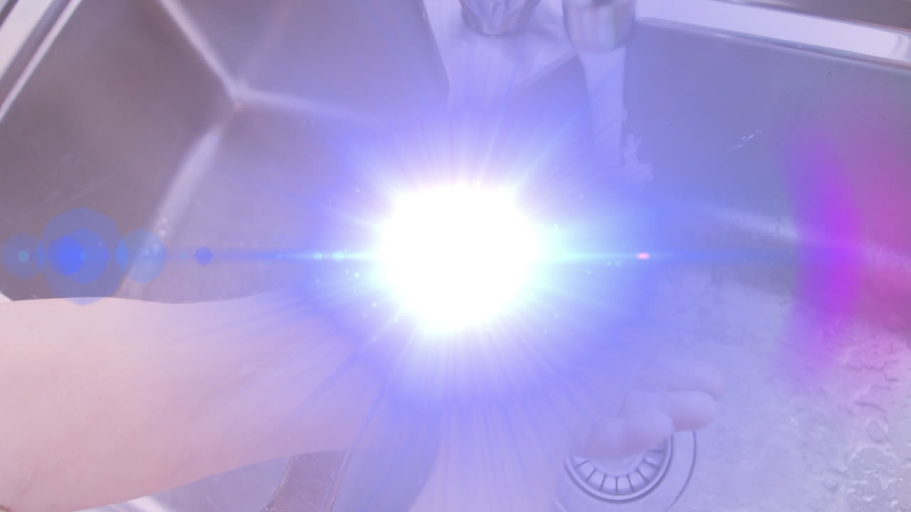 주방 싱크대에 손을  ⁇ 고 있는 고령 여성의 손 위로 움직이는 빛의 애니메이션