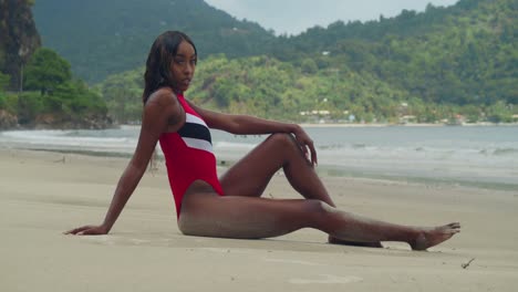 In-Trinidad,-a-young-girl-in-a-bikini-sits-in-the-sand-and-enjoys-the-tropical-beach