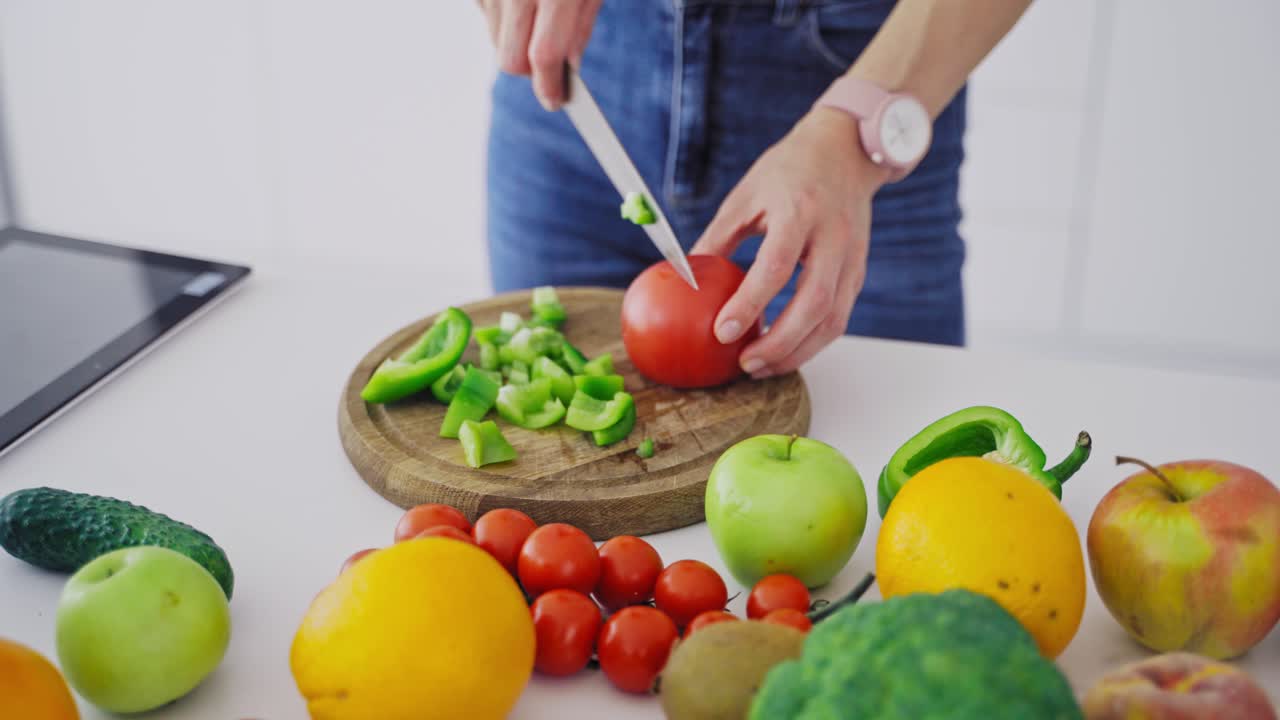 Female hands chopping fresh vegetables. Organic ingredients on the table and a woman preparing tasty salad. Healthy food and diet concept. Close-up.