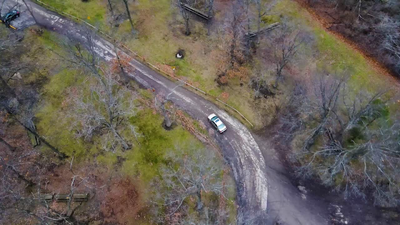 tiro de arriba hacia abajo siguiendo el coche en la carretera a través del bosque de otoño