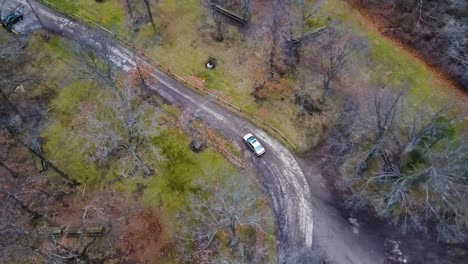 Top-down-shot-following-car-on-road-through-autumn-forest