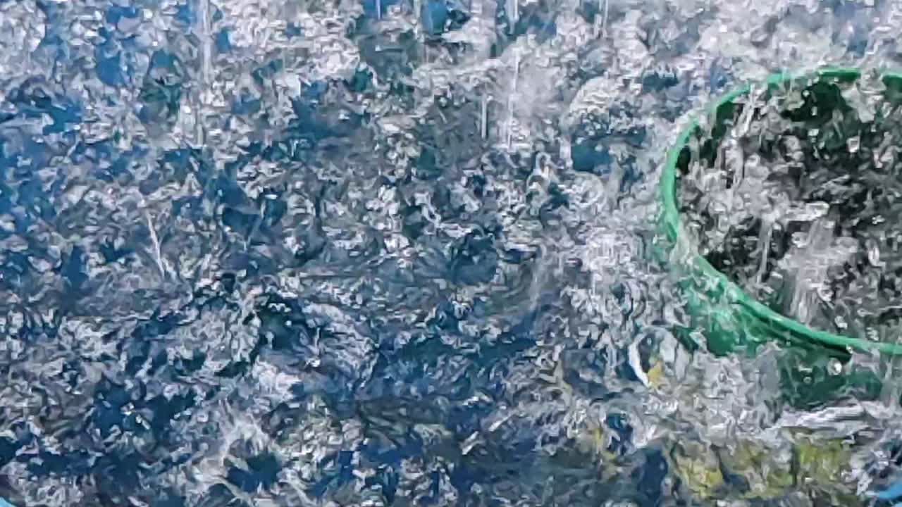 Torrential monsoon rain striking the brim of a water‑filled bucket beneath a corrugated carport in rural Surigao del Norte, Mindanao, Philippines.