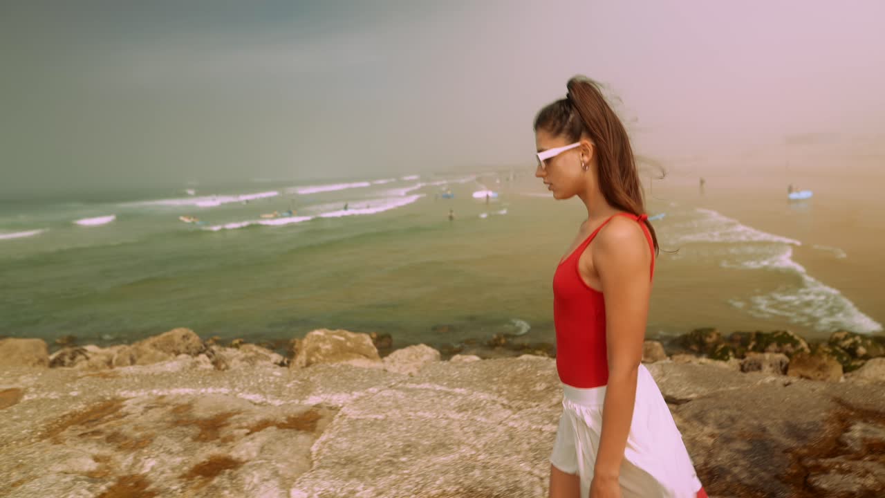 Young Woman Walking Along Rocky Beach Shoreline