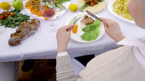 una anciana cortando su comida con un tenedor antes de comerla